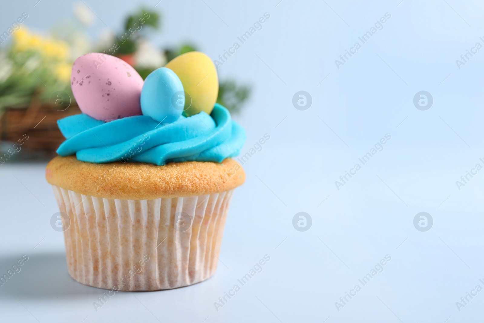 Photo of Tasty decorated Easter cupcake on light blue background, closeup. Space for text