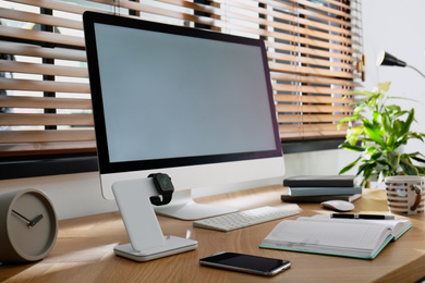 Photo of Modern workplace and watch charging with wireless pad