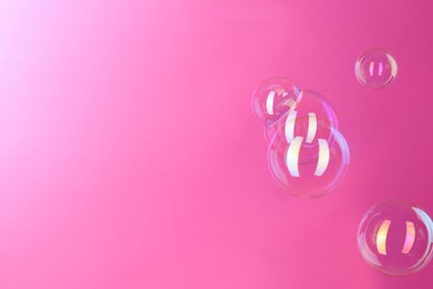 Photo of Beautiful transparent soap bubbles on pink background, space for text