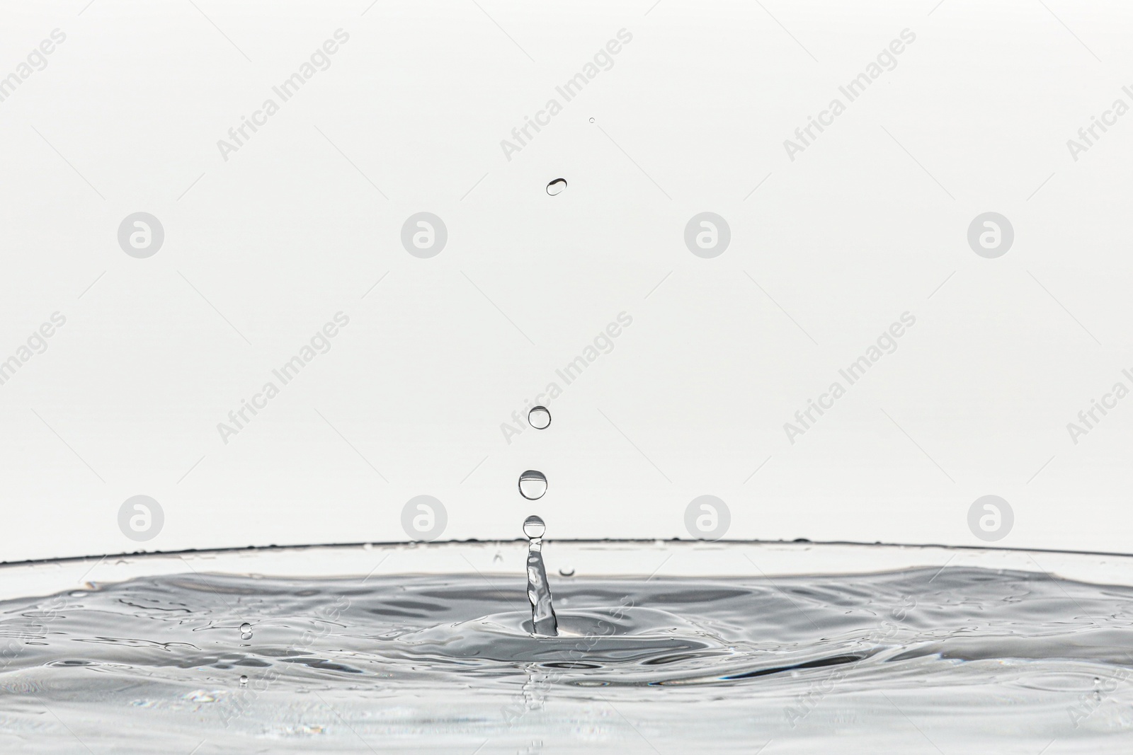 Photo of Splash of clear water with drops on light background, closeup