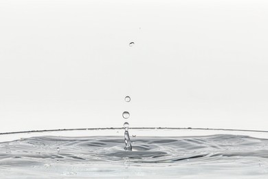 Photo of Splash of clear water with drops on light background, closeup