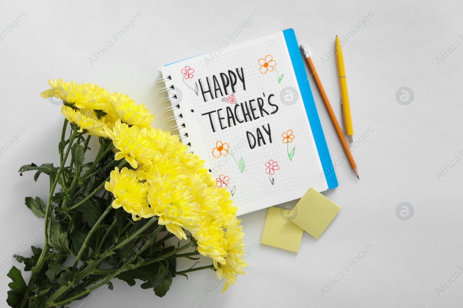 Photo of Beautiful flowers, stationery and notebook with words HAPPY TEACHER'S DAY on white background, flat lay