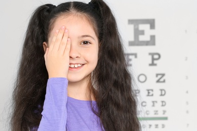 Cute little girl visiting children's doctor, space for text. Eye examination