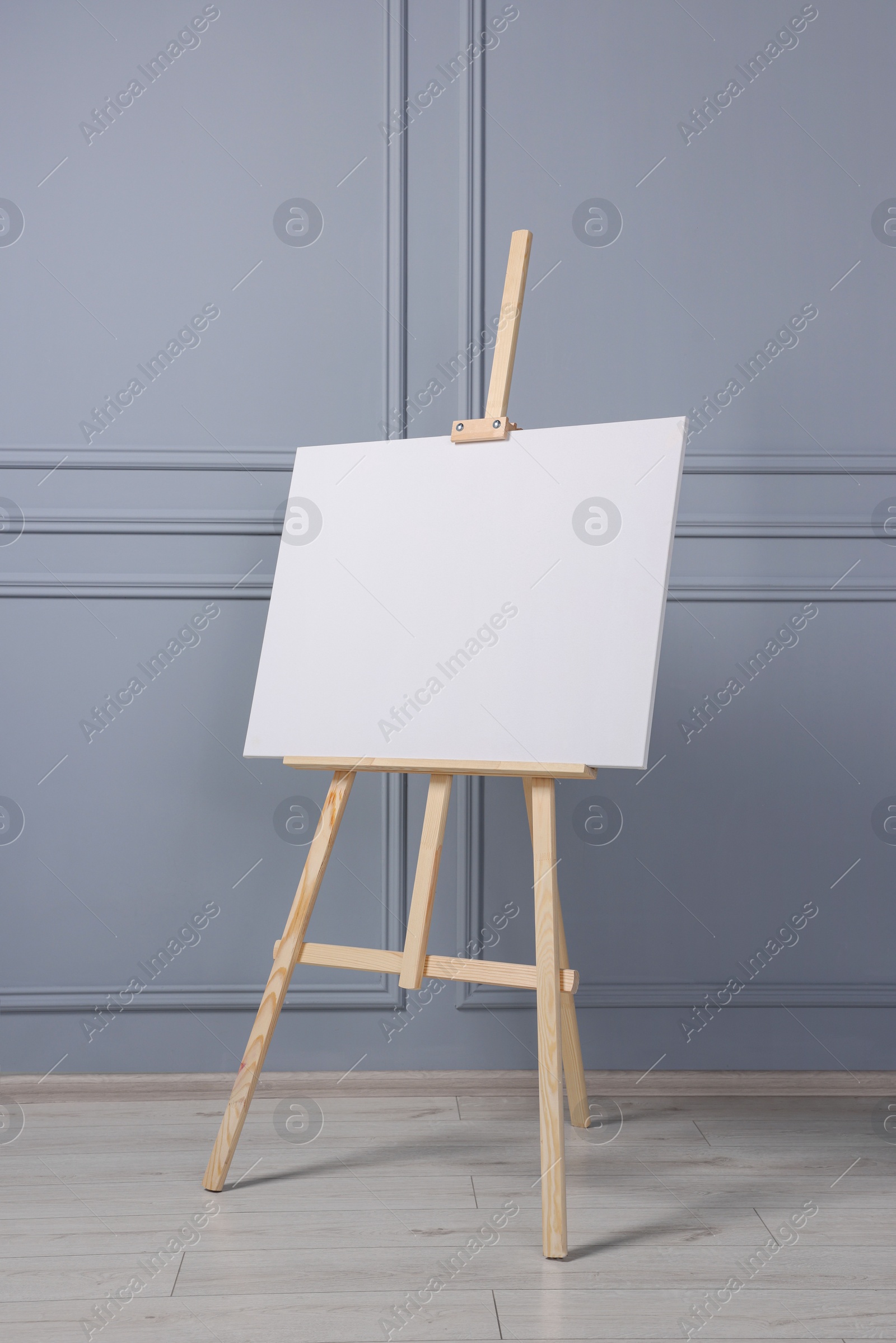 Photo of Wooden easel with blank canvas near grey wall indoors. Space for text