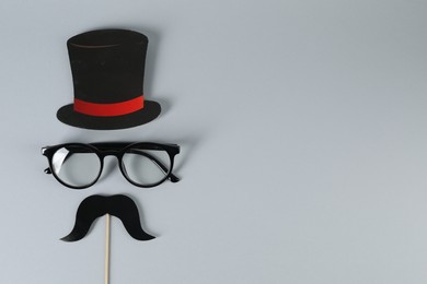 Photo of Fake mustache with party prop, paper hat and glasses on grey background, top view. Space for text