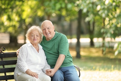 Photo of Elderly couple resting on bench in park