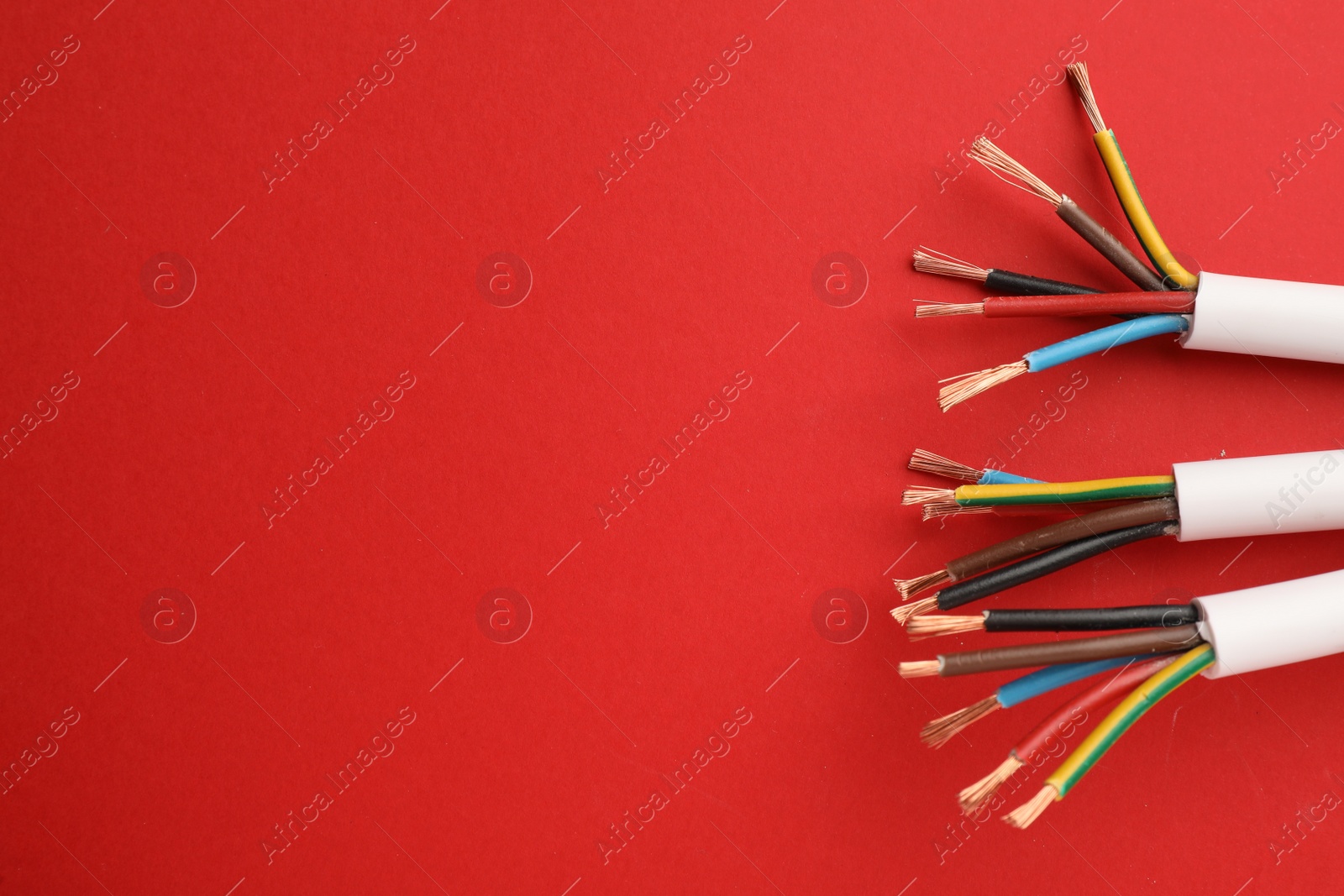 Photo of Electric cables with wires on red background, flat lay. Space for text