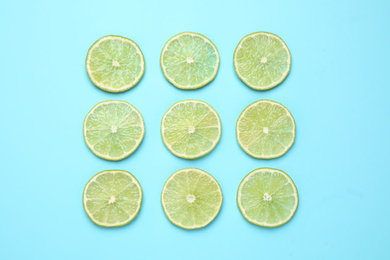 Fresh juicy lime slices on light blue background, flat lay