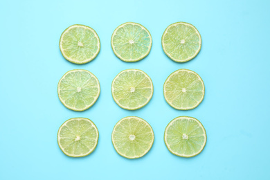 Photo of Fresh juicy lime slices on light blue background, flat lay