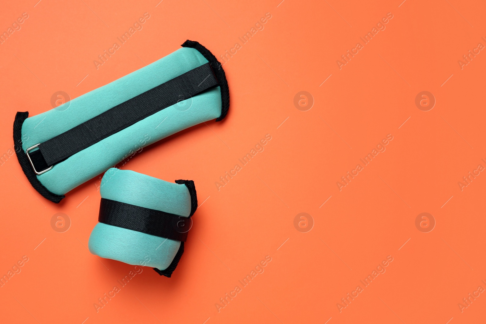 Photo of Turquoise weighting agents on orange background, flat lay. Space for text