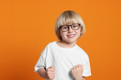 Photo of Cute little boy wearing glasses on orange background