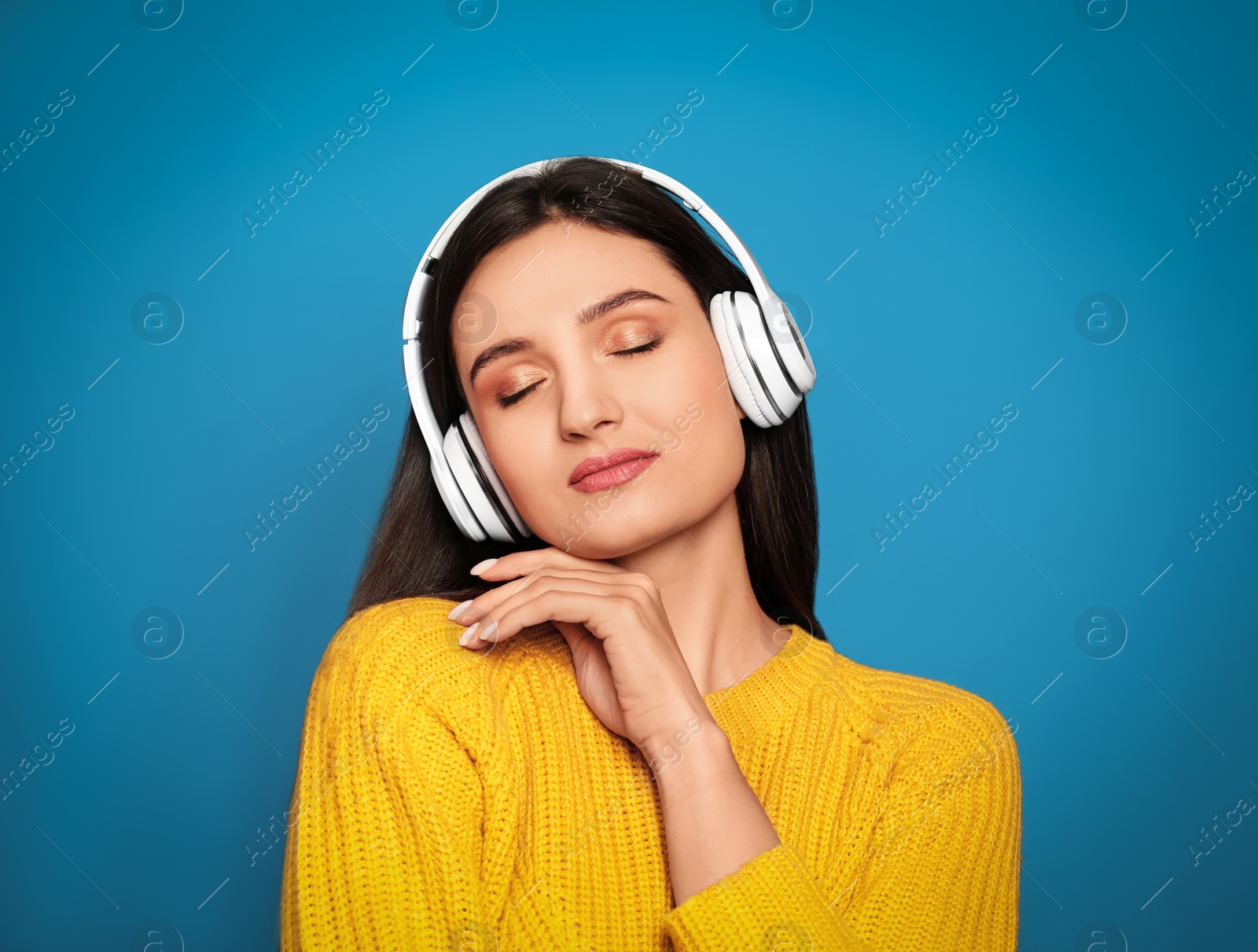 Photo of Young woman listening to audiobook on blue background