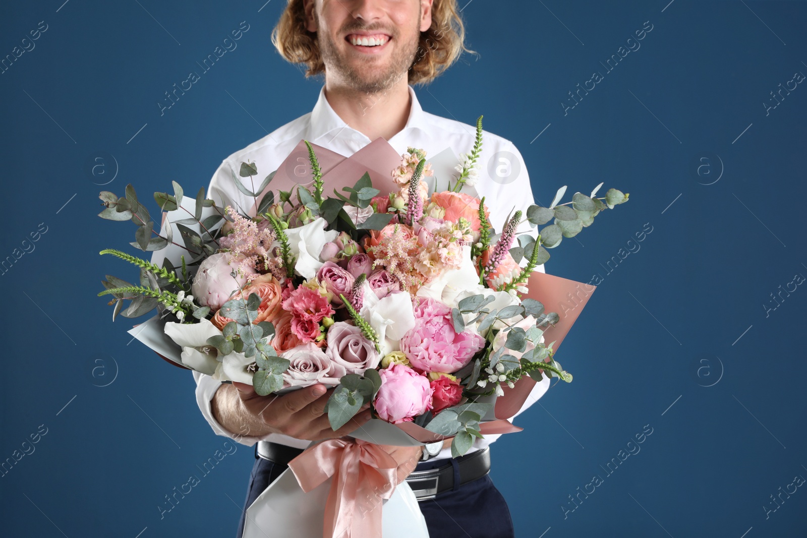 Photo of Man holding beautiful flower bouquet on blue background, closeup view