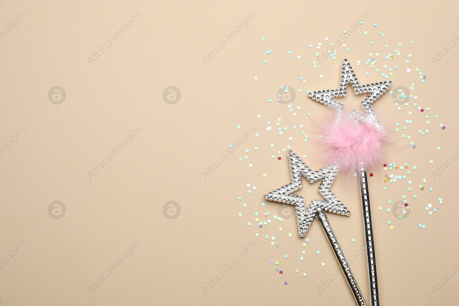 Photo of Beautiful silver magic wands and confetti on beige background, flat lay. Space for text