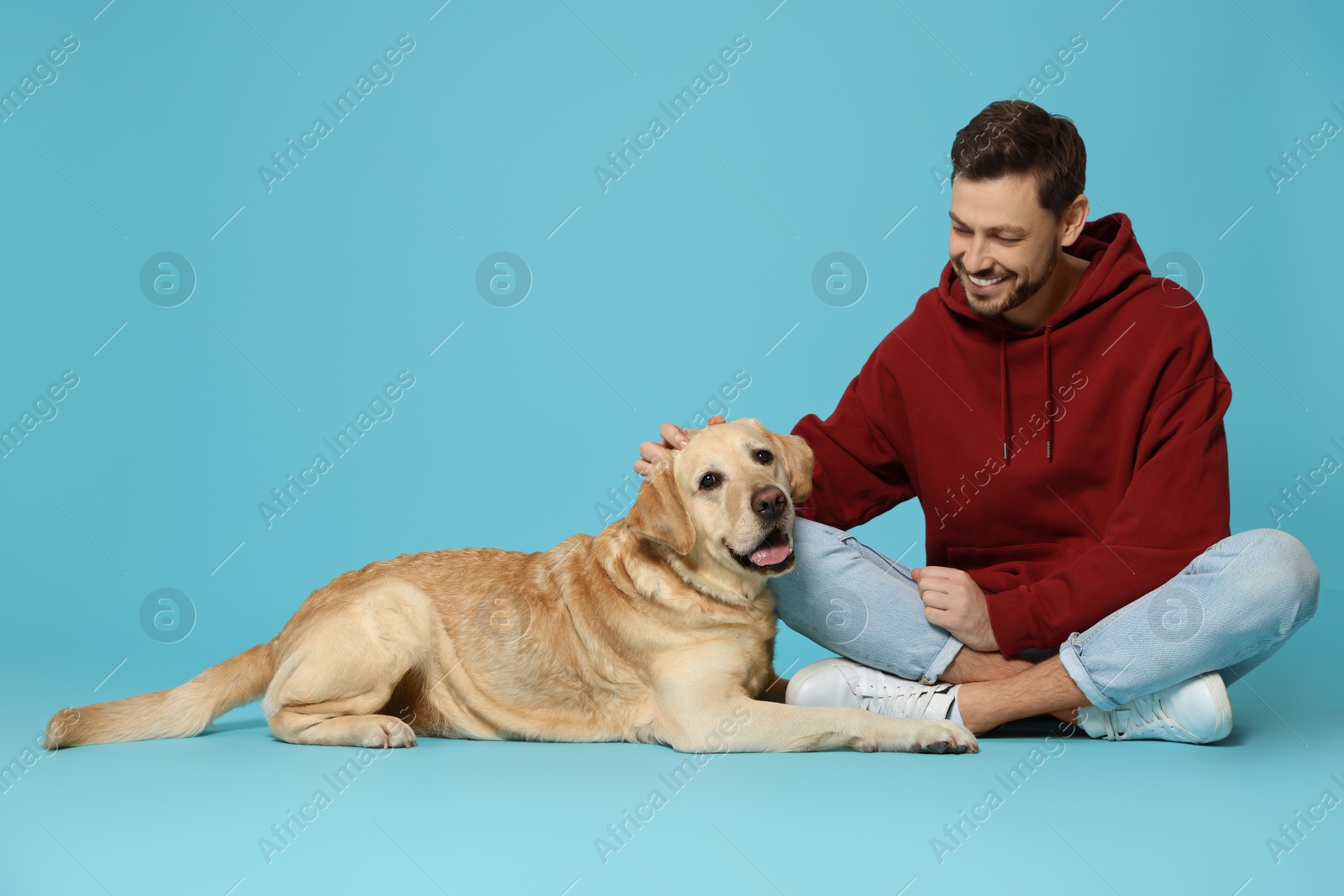 Photo of Happy man with his cute Labrador Retriever on turquoise background