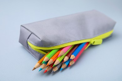 Many colorful pencils in pencil case on light grey background, closeup