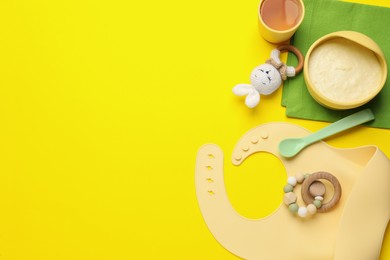 Photo of Healthy baby food in bowl and accessories on yellow background, flat lay. Space for text