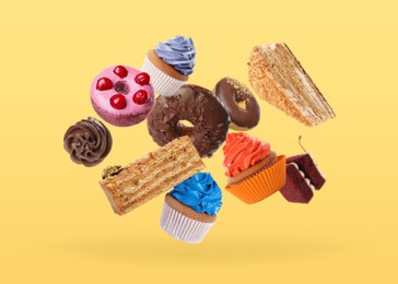 Image of Many different tasty tasty desserts falling on yellow background