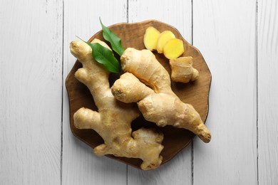 Photo of Fresh ginger with leaves on white wooden table, top view