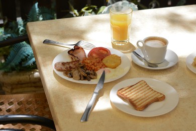 Delicious breakfast with fried meat and vegetables served on beige table in cafe