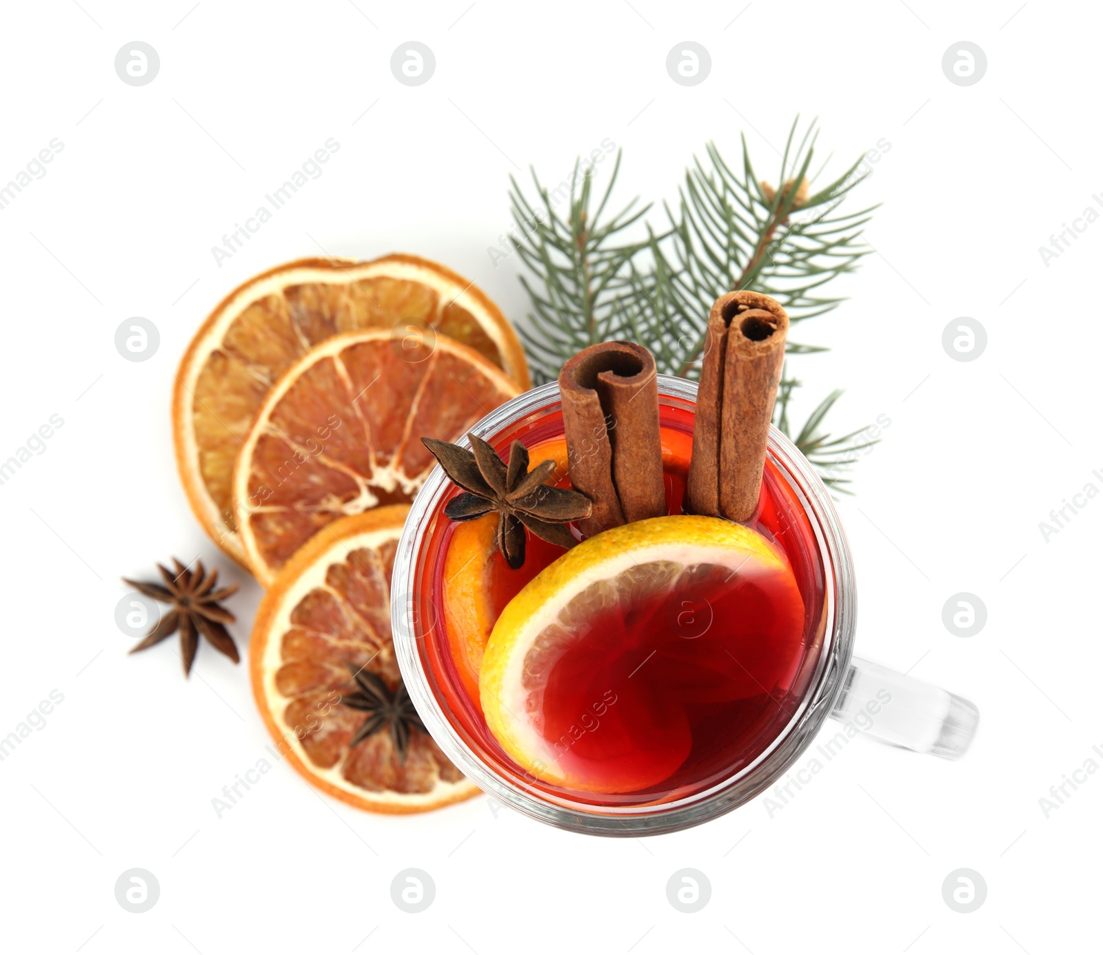 Photo of Glass cup of mulled wine, dried orange and fir branch on white background, top view