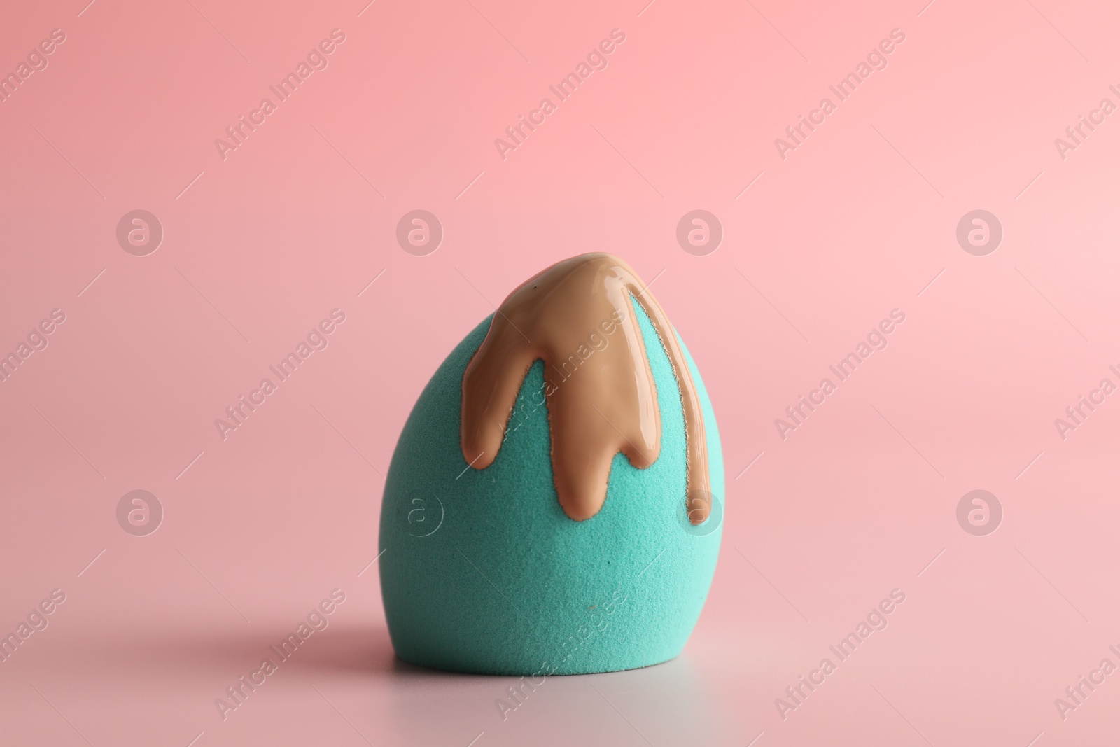 Photo of Makeup sponge with skin foundation on pink background