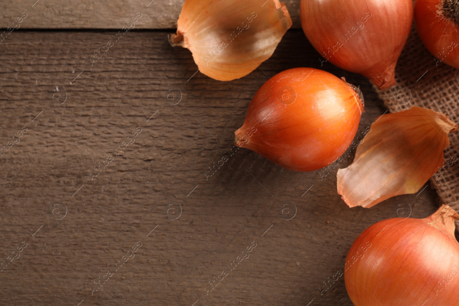 Photo of Many ripe onions on wooden table, flat lay. Space for text