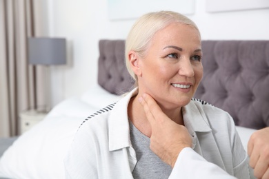 Man checking mature woman's pulse with fingers indoors