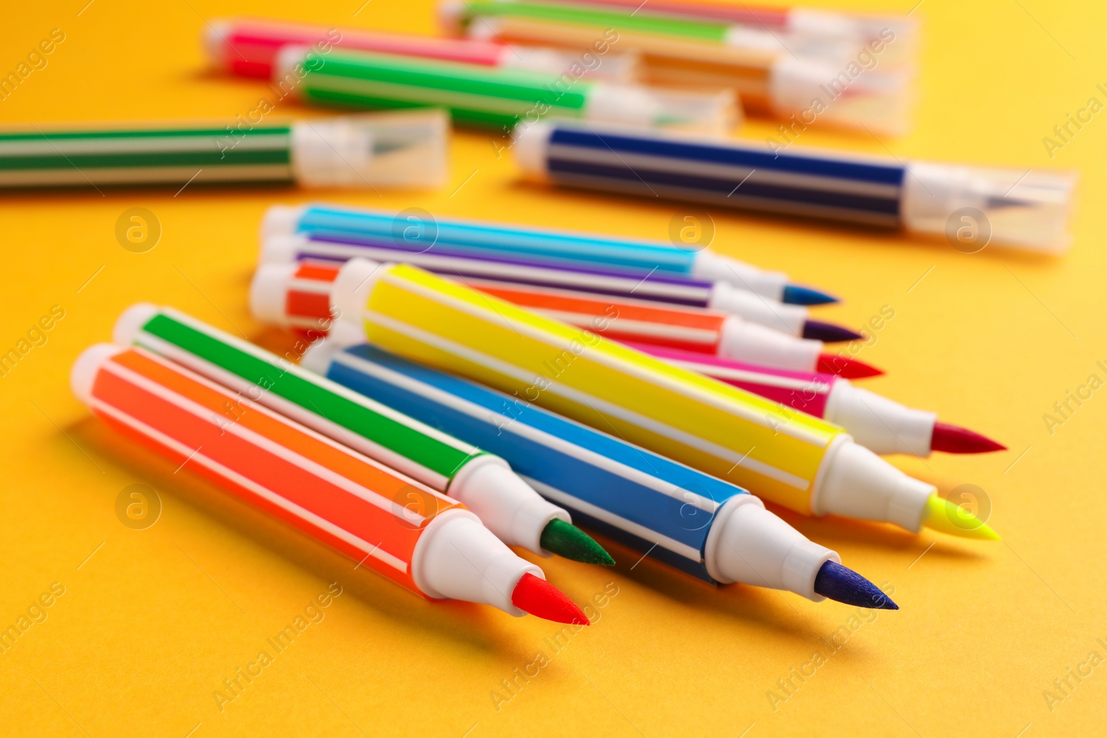 Photo of Many bright markers on yellow background, closeup