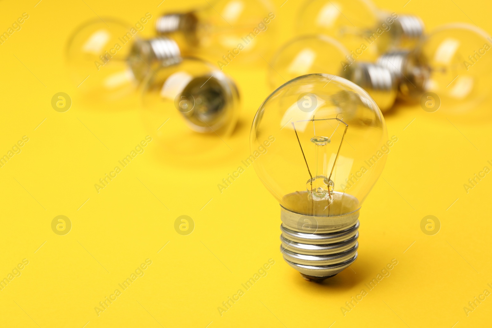 Photo of New incandescent lamp bulb on yellow background. Space for text