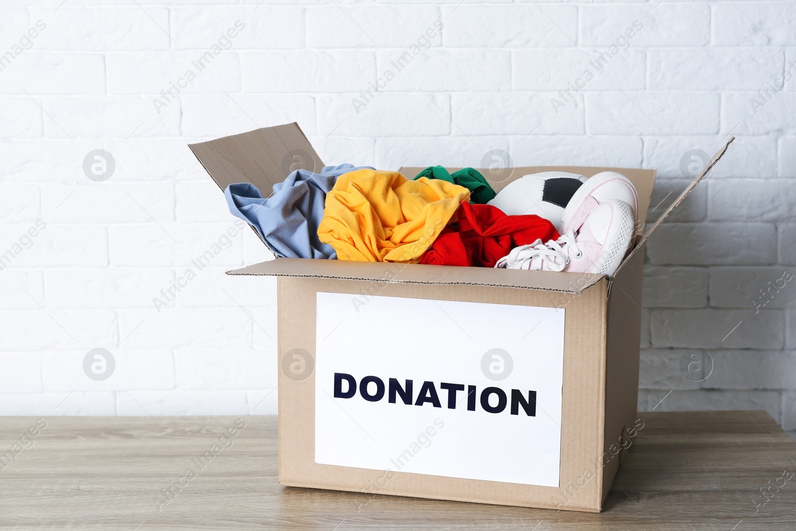 Photo of Carton box with donations on table near brick wall