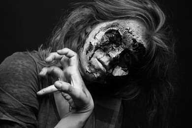 Scary zombie on dark background, black and white effect. Halloween monster