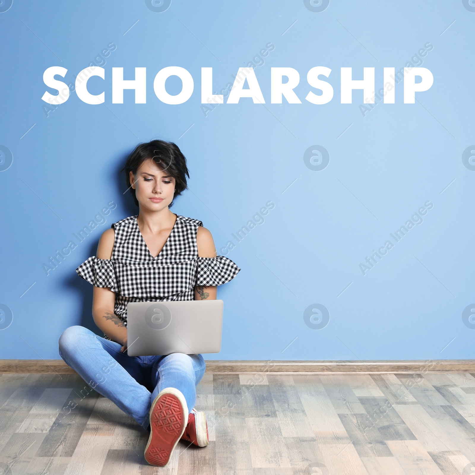 Image of Scholarship concept. Student with laptop sitting on floor near light blue wall