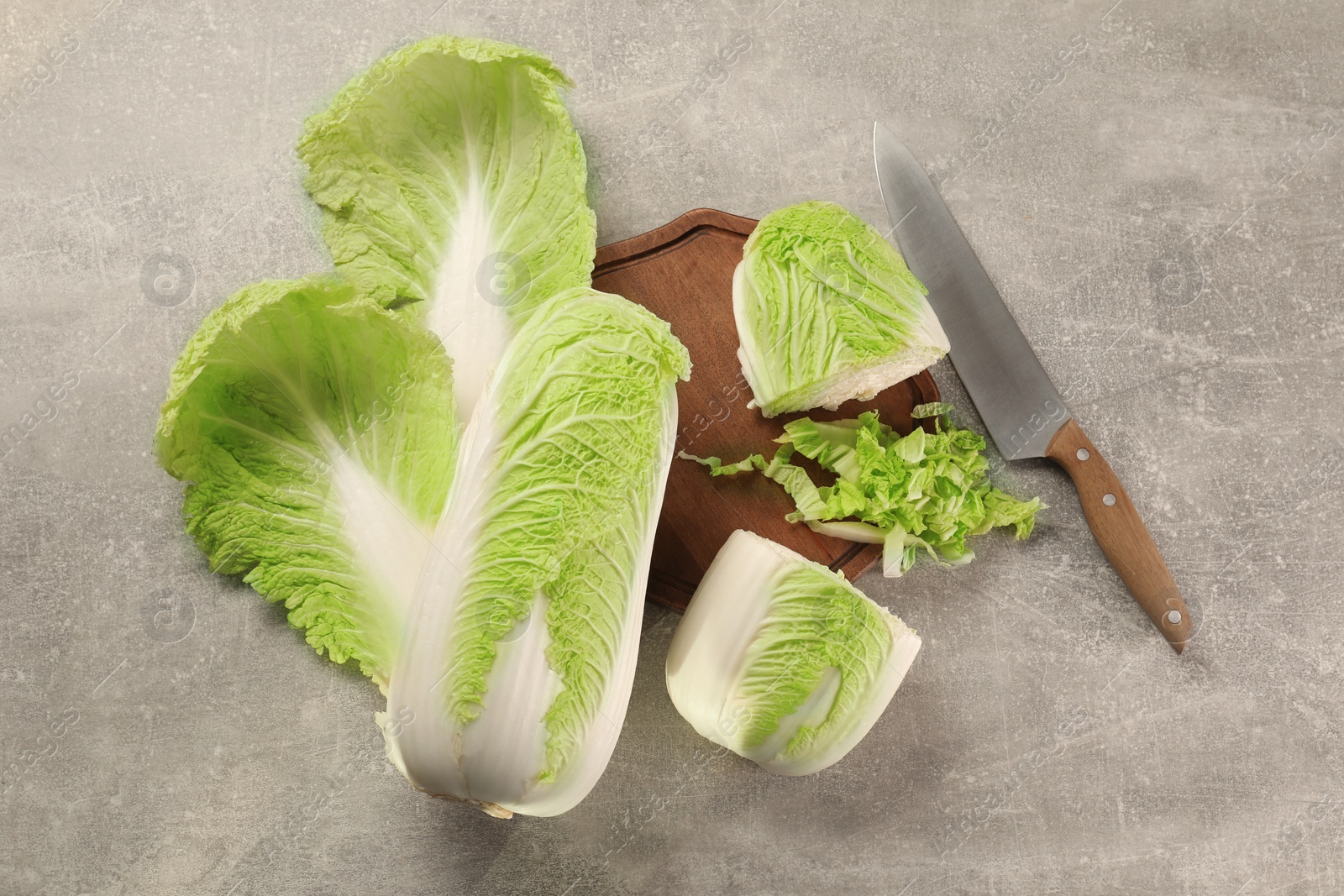 Photo of Whole and cut fresh Chinese cabbages on light grey table, flat lay