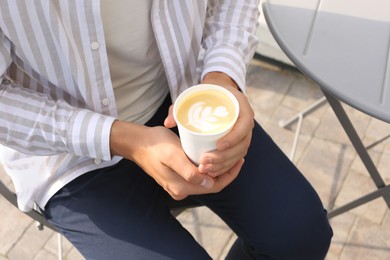 Photo of Coffee to go. Man with paper cup of drink outdoors, closeup