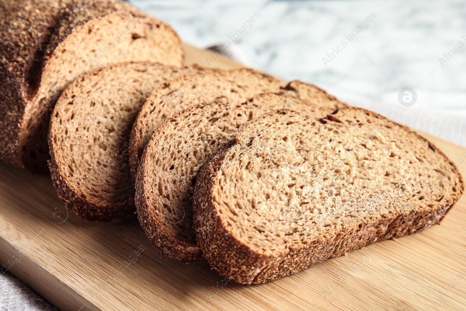 Photo of Tasty sliced bread on wooden board, closeup