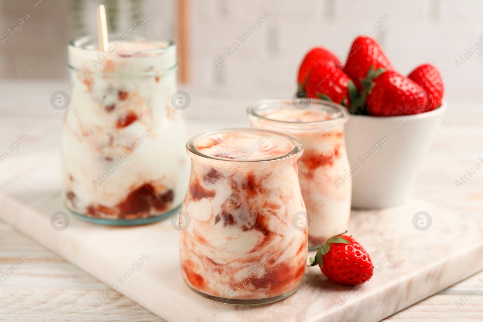 Photo of Tasty yoghurt with jam and strawberries on white wooden table, closeup