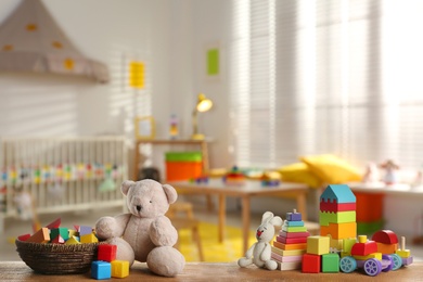 Set of different cute toys on wooden table in children's room. Space for text