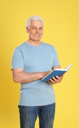 Photo of Senior man reading book on color background