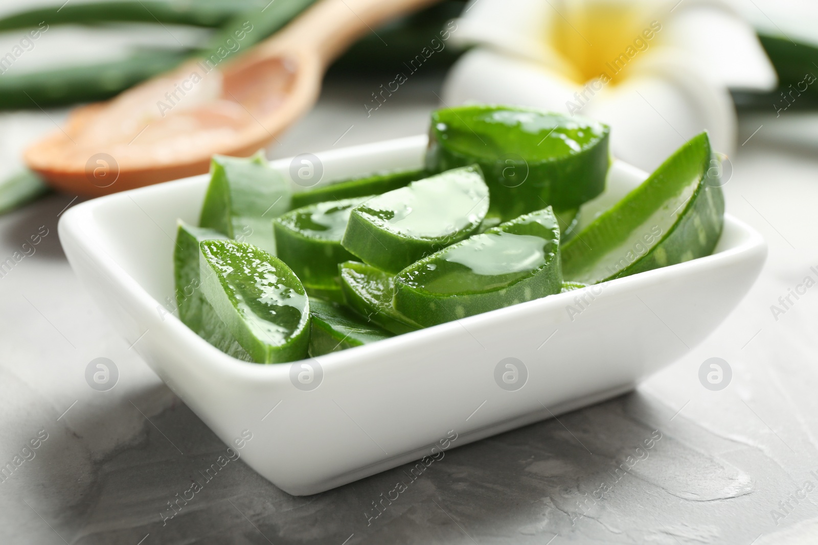 Photo of Bowl with sliced aloe vera leaves on gray table