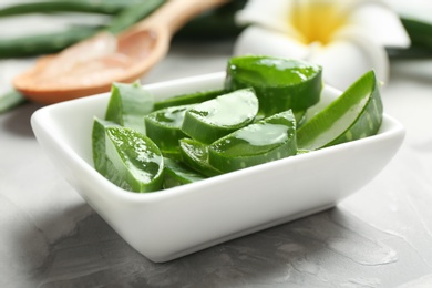 Bowl with sliced aloe vera leaves on gray table