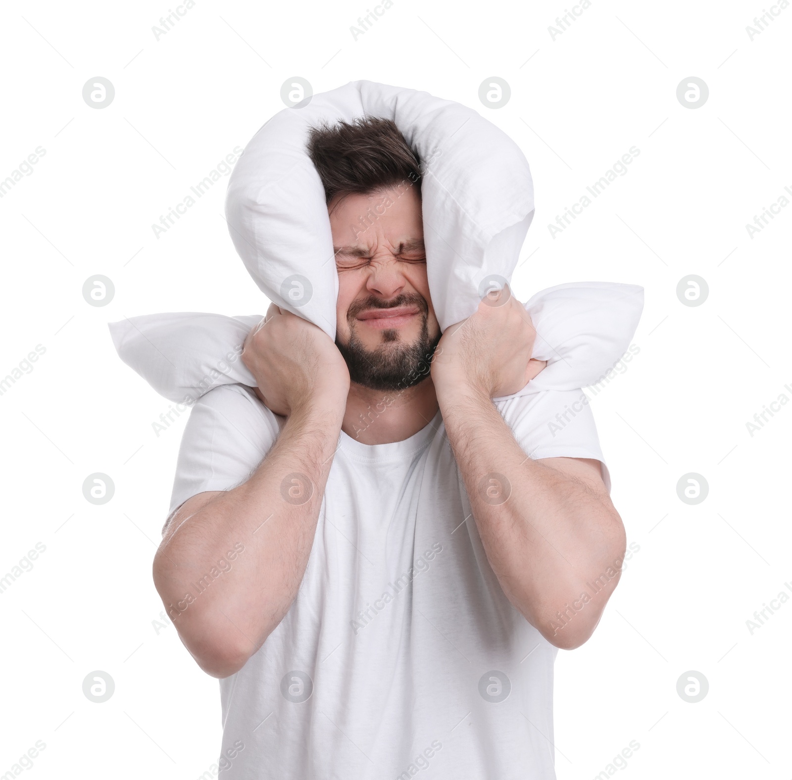 Photo of Tired man covering ears with pillow on white background. Insomnia problem