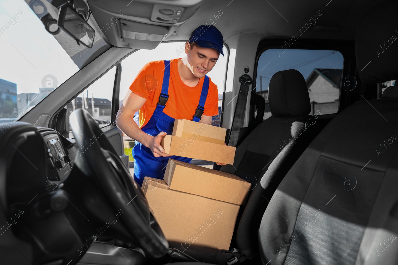 Photo of Courier taking parcels from car. Delivery service