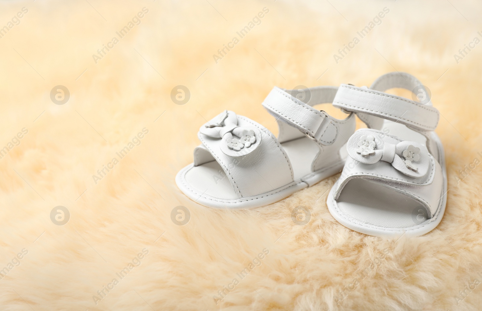 Photo of Pair of cute baby sandals on fuzzy fabric