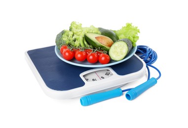 Photo of Skipping rope and bowl with different vegetables on scales isolated on white. Weight loss concept