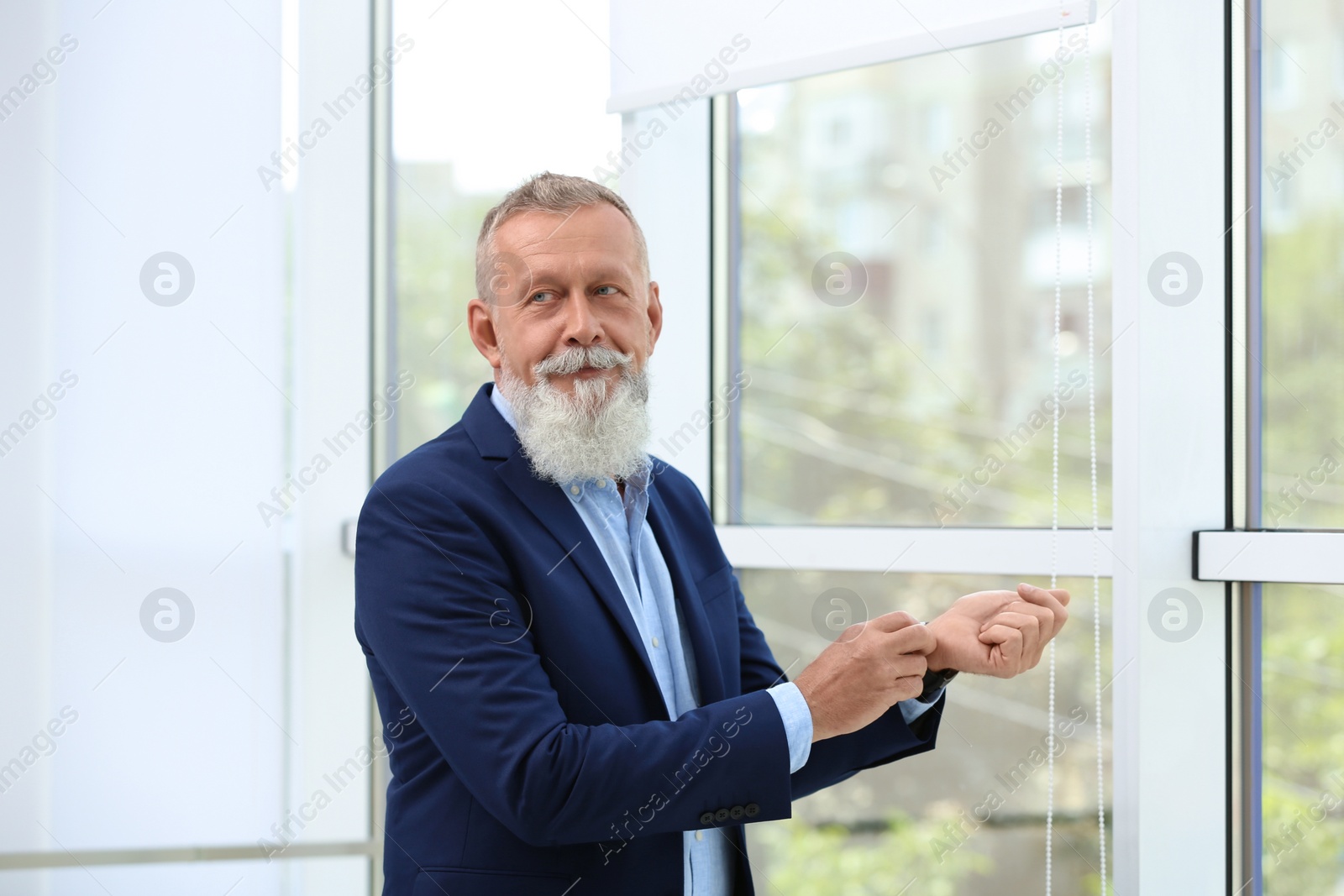 Photo of Portrait of handsome mature man in elegant suit near window