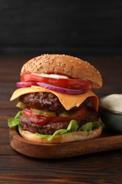 Photo of Tasty cheeseburger with patties and sauce on wooden table, closeup