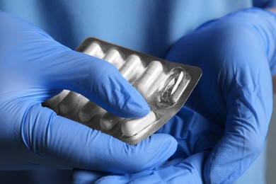 Photo of Doctor taking pill out from blister pack on grey background, closeup