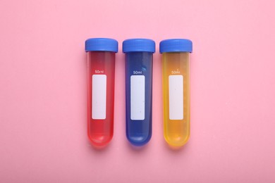 Photo of Test tubes with colorful liquids on pink background, flat lay. Kids chemical experiment set