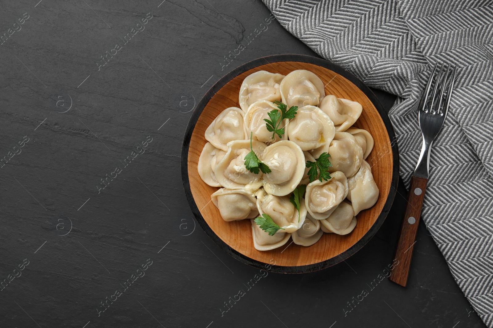 Photo of Tasty dumplings with parsley on black table, flat lay. Space for text